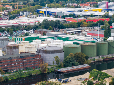 Aerial view of TanQuid Tanklager Berlin with large industrial storage tanks a barge on the canal and commercial buildings in the background in Berlin Berlin Germany.
