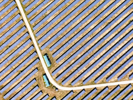 Aerial view of a large solar farm with long rows of blue photovoltaic panels and a winding dirt road in Torrazza Piemonte Piemonte Italy. Aerial view of a large solar farm with long rows of blue photovoltaic panels and a winding dirt road in Torrazza Piemonte Piemonte Italy.