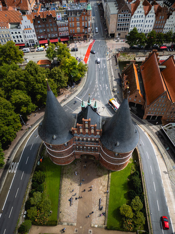 Aerial view of the iconic Holsten Gate standing proudly amidst the bustling streets and verdant parks its dark spires contrasting with the bright cityscape L&uuml;beck Schleswig Holstein Germany.