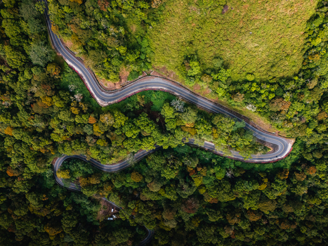 Aerial view of a winding road cutting through the lush green forest of the Sembalun agricultural basin at the foothills of Mount Rinjani Sembalun West Nusa Tenggara Indonesia. Aerial view of a winding road cutting through the lush green forest of the Sembalun agricultural basin at the foothills of Mount Rinjani Sembalun West Nusa Tenggara Indonesia.