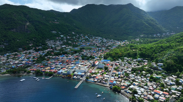 Aerial view of the coastal town of Soufriere nestled between lush green mountains and the Caribbean Sea featuring colorful buildings a pier and boats in Soufriere Soufriere Saint Lucia.