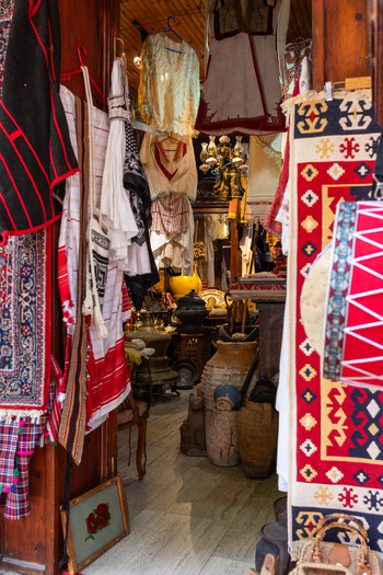 View of traditional Albanian textiles embroidered clothing and antique pottery displayed in a rustic shop at the Old Bazaar in Kruje Durres County Albania.