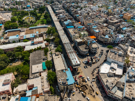Aerial view of the urban landscape of Udaipur featuring dense residential and commercial buildings a prominent elevated construction project and surrounding greenery in Udaipur Rajasthan India.