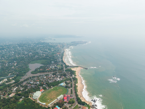 Aerial view of the Galle International Stadium and the sandy coastline with waves crashing against the shore in Galle Southern Province Sri Lanka. Aerial view of the Galle International Stadium and the sandy coastline with waves crashing against the shore in Galle Southern Province Sri Lanka.
