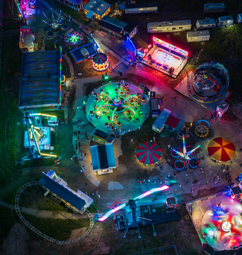 Aerial view of a vibrant amusement park at night featuring illuminated carnival rides colorful lights and people walking through the fairground in Vilnius Vilnius County Lithuania. Aerial view of a vibrant amusement park at night featuring illuminated carnival rides colorful lights and people walking through the fairground in Vilnius Vilnius County Lithuania.