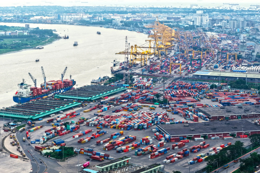 Aerial view of Chattogram Port featuring numerous colorful shipping containers large cargo ships docked along the river and industrial cranes in Chittagong Chittagong Division Bangladesh.