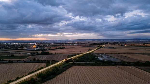 Aerial view of a road stretching through agricultural fields at dusk with a dramatic cloudy sky in Sremska Mitrovica Vojvodina Serbia. Aerial view of a road stretching through agricultural fields at dusk with a dramatic cloudy sky in Sremska Mitrovica Vojvodina Serbia.