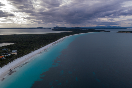 Aerial view of Frenchman Bay featuring turquoise waters a pristine white sandy beach and dense coastal vegetation under a dramatic cloudy sky in Albany Western Australia Australia. Aerial view of Frenchman Bay featuring turquoise waters a pristine white sandy beach and dense coastal vegetation under a dramatic cloudy sky in Albany Western Australia Australia.