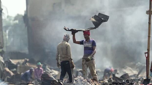 View of men working amidst smoke and debris in Dhaka Bangladesh. View of men working amidst smoke and debris in Dhaka Bangladesh.