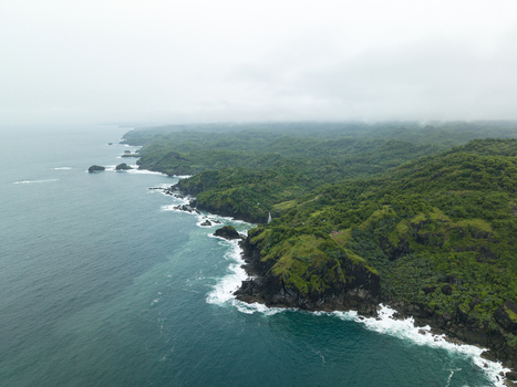 Aerial view of Pengilon Hill s dramatic cliffs meet the turquoise sea under a misty sky Gunungkidul Regency Daerah Istimewa Yogyakarta Indonesia. Aerial view of Pengilon Hill s dramatic cliffs meet the turquoise sea under a misty sky Gunungkidul Regency Daerah Istimewa Yogyakarta Indonesia.