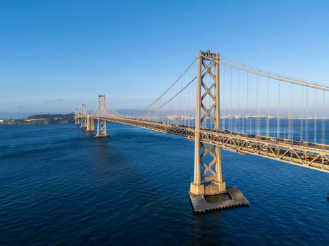 Aerial view of the San Francisco Oakland Bay Bridge spanning the deep blue waters of the bay with traffic on the steel structure in San Francisco California United States. Aerial view of the San Francisco Oakland Bay Bridge spanning the deep blue waters of the bay with traffic on the steel structure in San Francisco California United States.