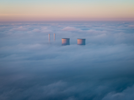 Aerial view of RWE Clauscentrale power plant cooling towers and chimneys emerging from a thick layer of fog under a soft dawn sky Maasbracht Limburg Netherlands. Aerial view of RWE Clauscentrale power plant cooling towers and chimneys emerging from a thick layer of fog under a soft dawn sky Maasbracht Limburg Netherlands.