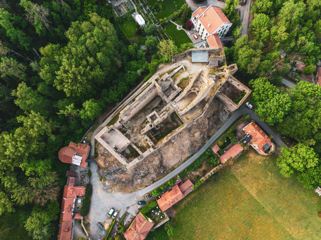 Aerial view of the historic ruins of Okor Castle surrounded by lush green forests meadows and red tiled houses in Okor Central Bohemian Region Czechia. Aerial view of the historic ruins of Okor Castle surrounded by lush green forests meadows and red tiled houses in Okor Central Bohemian Region Czechia.