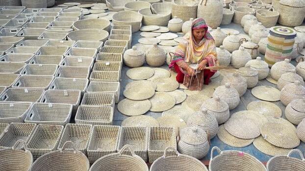 View of a woman weaving wicker baskets in Bogura Bangladesh. View of a woman weaving wicker baskets in Bogura Bangladesh.