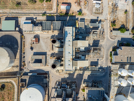 Aerial view of a power plant facility featuring large storage tanks industrial chimneys and complex infrastructure in Chania Greece.