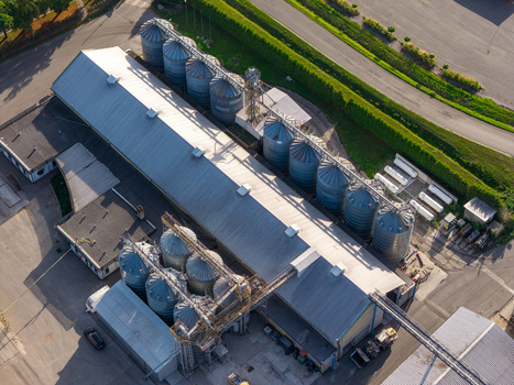 Aerial view of large grain bins at a storage facility with metal silos metal roofs and industrial infrastructure in Poland.