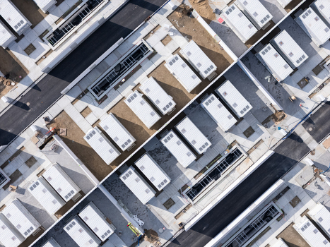 Aerial view of rows of white industrial containers arranged in a construction site with paved roads and infrastructure in Poland.