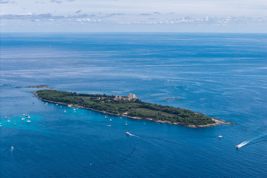 Aerial view of Ile Sainte Marguerite with its historic fort lush greenery and surrounding turquoise Mediterranean waters in Cannes Provence Alpes Cote d Azur France. Aerial view of Ile Sainte Marguerite with its historic fort lush greenery and surrounding turquoise Mediterranean waters in Cannes Provence Alpes Cote d Azur France.