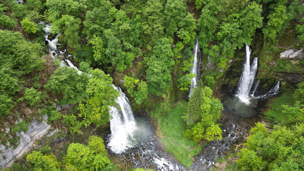Aerial view of the Cascades du Flumen waterfalls plunging through dense green forest and rocky cliffs Septmoncel Les Molunes Bourgogne Franche Comte France. Aerial view of the Cascades du Flumen waterfalls plunging through dense green forest and rocky cliffs Septmoncel Les Molunes Bourgogne Franche Comte France.