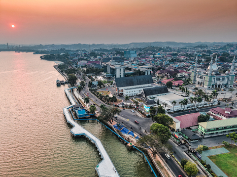 Aerial view of the Islamic Center of Samarinda with its distinctive domes and minarets situated along the Mahakam River under a golden sunset sky in Samarinda East Kalimantan Indonesia. Aerial view of the Islamic Center of Samarinda with its distinctive domes and minarets situated along the Mahakam River under a golden sunset sky in Samarinda East Kalimantan Indonesia.