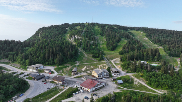 Aerial view of Col de la Faucille mountain resort with ski lifts lush green forests and alpine buildings in Gex Auvergne Rhone Alpes France.