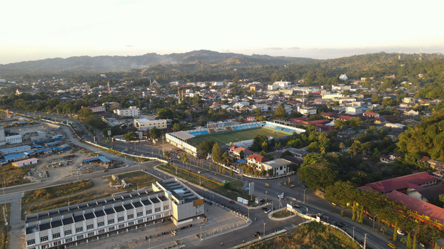Aerial view of the city of Sorong featuring a stadium urban infrastructure and surrounding hills in Sorong Southwest Papua Indonesia. Aerial view of the city of Sorong featuring a stadium urban infrastructure and surrounding hills in Sorong Southwest Papua Indonesia.