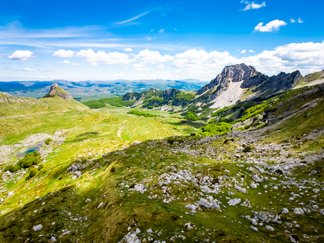 Aerial view of Bobotov Kuk peak surrounded by lush green slopes and rocky terrain in Durmitor National Park Zabljak Municipality Montenegro. Aerial view of Bobotov Kuk peak surrounded by lush green slopes and rocky terrain in Durmitor National Park Zabljak Municipality Montenegro.