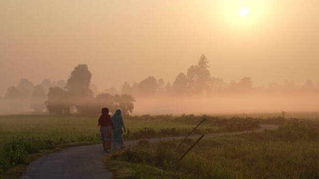 View of people walking in a misty rural landscape Bangladesh.