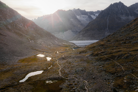 Aerial view of the Aletsch Glacier surrounded by dramatic mountain peaks winding hiking trails and small alpine pools in the valley of Fieschertal Valais Switzerland. Aerial view of the Aletsch Glacier surrounded by dramatic mountain peaks winding hiking trails and small alpine pools in the valley of Fieschertal Valais Switzerland.