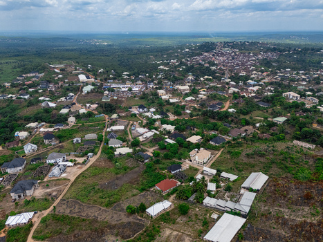 Aerial view of a sprawling settlement with diverse architecture nestled amidst verdant hills and earthy paths under hazy skies Ohafia Abia Nigeria. Aerial view of a sprawling settlement with diverse architecture nestled amidst verdant hills and earthy paths under hazy skies Ohafia Abia Nigeria.