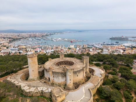 Aerial view of Castillo de Bellver with its unique circular structure and towers overlooking the harbor and city skyline in Palma Illes Balears Spain.