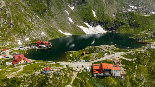Aerial view of Balea Lake surrounded by rugged mountain peaks chalets and winding roads in the Romanian Carpathians Curtea de Arges Judetul Arges Romania.