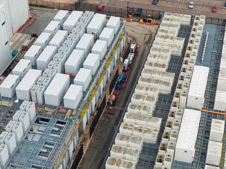 Aerial view of a data center facility with rows of white server containers and industrial cooling units in the United Kingdom.