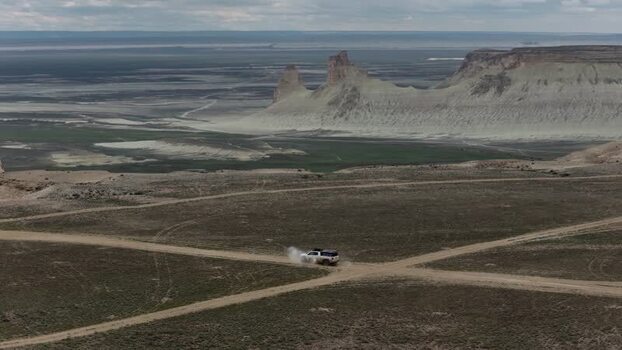 Aerial view of an SUV driving near Bozjyra rock formations Kazakhstan. Aerial view of an SUV driving near Bozjyra rock formations Kazakhstan.