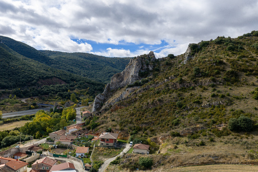 Aerial view of the rocky landscape and village featuring stone houses rolling hills and a highway winding through the valley under a cloudy sky in Ameyugo Castile and Leon Spain.
