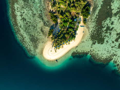 Aerial view of Pass Island with its white sand beach lush tropical vegetation and surrounding coral reefs in the clear turquoise waters of Coron Philippines. Aerial view of Pass Island with its white sand beach lush tropical vegetation and surrounding coral reefs in the clear turquoise waters of Coron Philippines.
