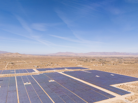 Aerial view of a vast solar farm with rows of blue panels across the arid desert landscape under a clear sky in Lucerne Valley California United States. Aerial view of a vast solar farm with rows of blue panels across the arid desert landscape under a clear sky in Lucerne Valley California United States.