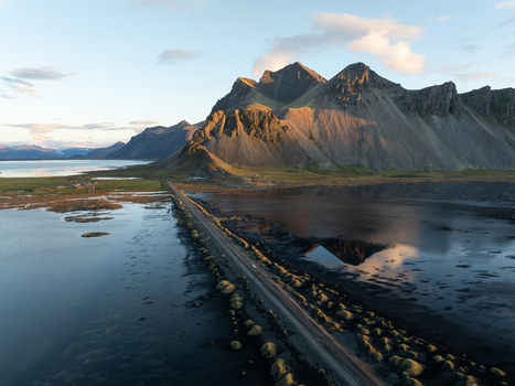 Aerial view of rugged mountains meet the serene waters in a dance of light and shadow connected by a slender road Höfn Iceland. Aerial view of rugged mountains meet the serene waters in a dance of light and shadow connected by a slender road Höfn Iceland.