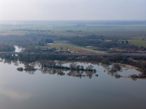 Aerial view of flooded river banks with submerged trees a highway bridge and rural landscape under a hazy sky in Kaniukai Kaunas County Lithuania. Aerial view of flooded river banks with submerged trees a highway bridge and rural landscape under a hazy sky in Kaniukai Kaunas County Lithuania.