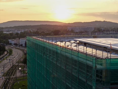 Aerial view of a building under renovation covered in green safety mesh with tram tracks running alongside in the urban landscape of Krakow Lesser Poland Voivode Poland.