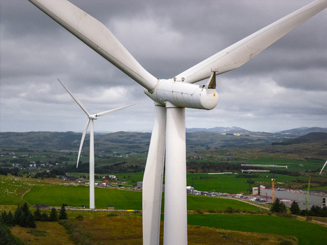 Aerial view of the Hog Jaeren wind farm featuring large white wind turbines set against rolling green hills and a cloudy sky in Ha Municipality Rogaland Norway. Aerial view of the Hog Jaeren wind farm featuring large white wind turbines set against rolling green hills and a cloudy sky in Ha Municipality Rogaland Norway.
