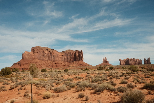 View of Monument Valley with its towering red sandstone buttes and mesas under a blue sky with wispy clouds San Juan County Utah United States.