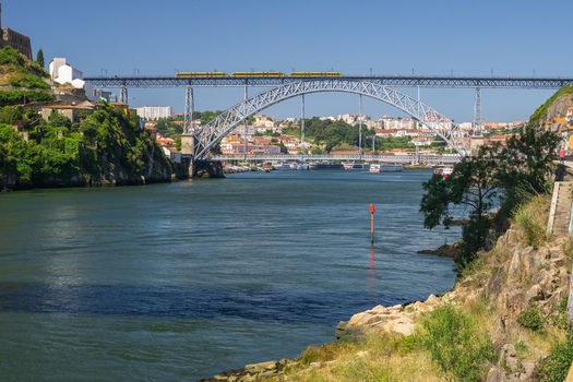 Porto Portugal 13 July 2021 View of the Dom Luís I Bridge arching gracefully over the Douro River connecting vibrant cityscapes under a clear sky. Porto Portugal 13 July 2021 View of the Dom Luís I Bridge arching gracefully over the Douro River connecting vibrant cityscapes under a clear sky.