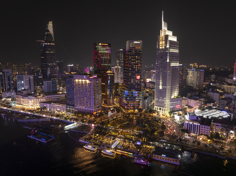 Aerial view of the illuminated skyline at night featuring the Bitexco Financial Tower and the Saigon River waterfront with city lights in Ho Chi Minh City Ho Chi Minh Vietnam. Aerial view of the illuminated skyline at night featuring the Bitexco Financial Tower and the Saigon River waterfront with city lights in Ho Chi Minh City Ho Chi Minh Vietnam.