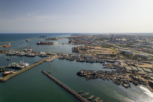 Aerial view of ships docked in the harbor juxtaposed with the cityscape under a clear sky creating a contrast of industrial activity and urban life Tema Ghana. Aerial view of ships docked in the harbor juxtaposed with the cityscape under a clear sky creating a contrast of industrial activity and urban life Tema Ghana.