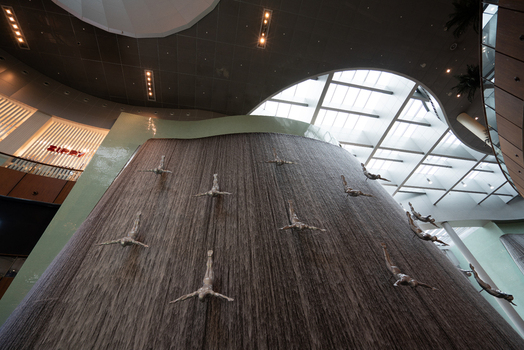 View of the Human Waterfall sculpture featuring silver divers on a large indoor water feature inside The Dubai Mall in Dubai Dubai United Arab Emirates. View of the Human Waterfall sculpture featuring silver divers on a large indoor water feature inside The Dubai Mall in Dubai Dubai United Arab Emirates.