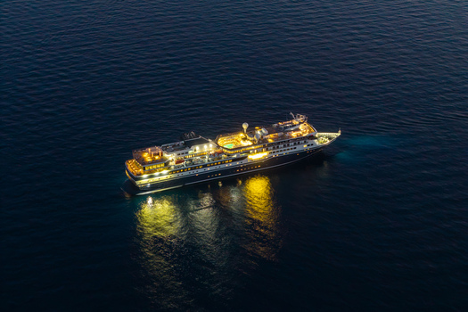 Aerial view of a luxury cruise ship illuminated at night with glowing lights reflecting on the dark sea surface near Eze Provence Alpes Cote d Azur France. Aerial view of a luxury cruise ship illuminated at night with glowing lights reflecting on the dark sea surface near Eze Provence Alpes Cote d Azur France.