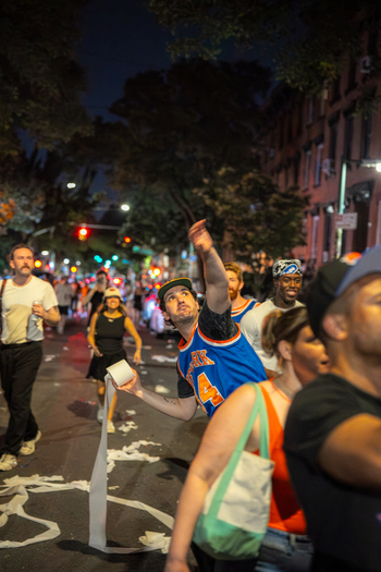 Williamsburg Brooklyn USA 14 June 2026 View of a fan in a basketball jersey throwing toilet paper during street celebrations for the New York Knicks in an urban neighborhood at night. Williamsburg Brooklyn USA 14 June 2026 View of a fan in a basketball jersey throwing toilet paper during street celebrations for the New York Knicks in an urban neighborhood at night.
