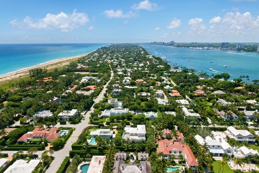 Aerial view of luxury waterfront estates and lush tropical greenery along the peninsula between the Atlantic Ocean and the Intracoastal Waterway in Palm Beach Florida United States.