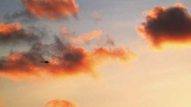 View of a helicopter flying through sunset clouds Brazil.